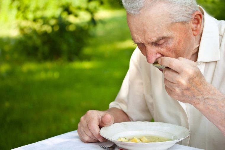 Portrait of a senior man eating a soup outdoor