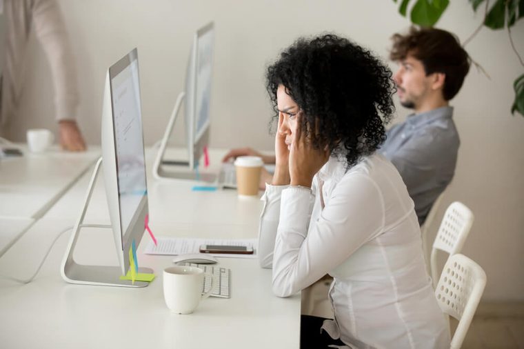 Stressed young african american businesswoman suffering from headache migraine touching temples at workplace, frustrated black woman employee tired from computer work can not concentrate or focus