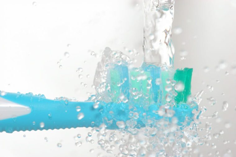 electrical toothbrush closeup under water tap