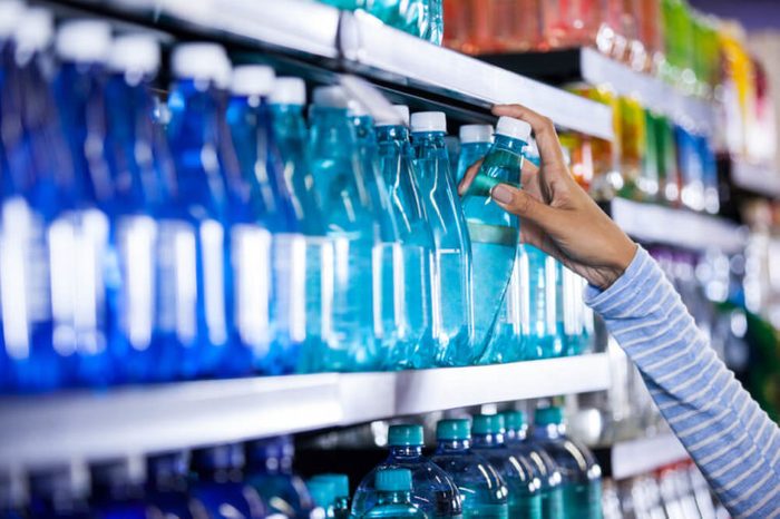 Woman picking bottle of water in grocery section of supermarket