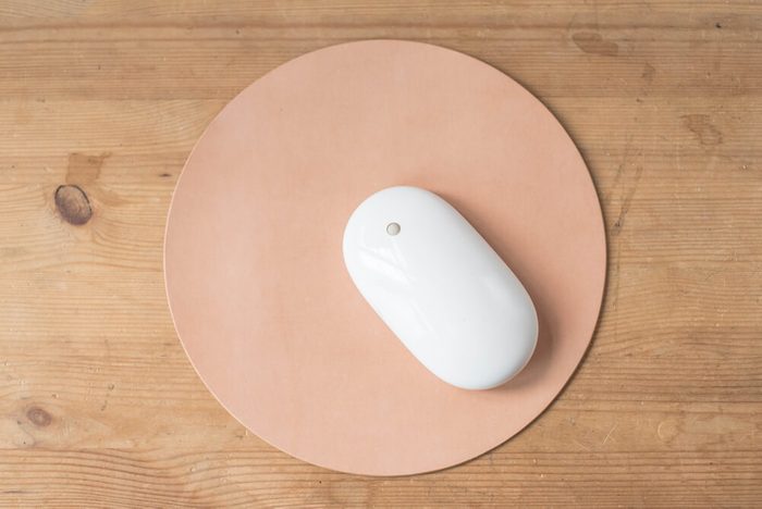 White wireless mouse on a round mouse pad on a wooden surface