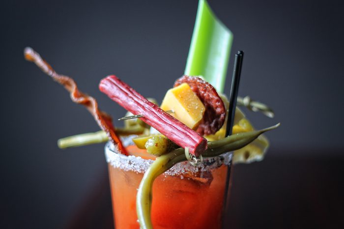 Close up Bloody Mary cocktail with tomato juice plus bacon, pickle, celery, jerky, and olive garnish