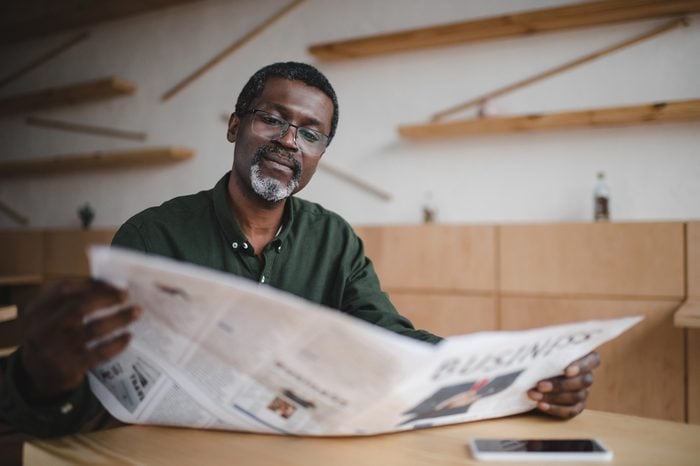 mature african american businessman reading newspaper in cafe