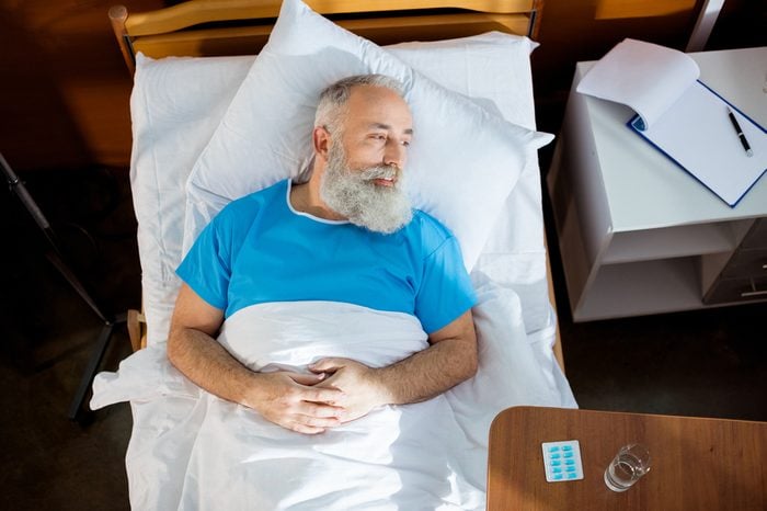 Top view of senior bearded man lying in hospital bed and lookig at distance