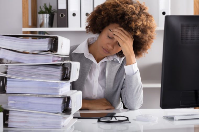 Stressful Afro American Businesswoman Sitting In Office With Stacked Of Files