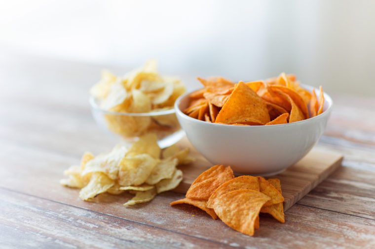 close up of potato crisps and nachos in glass bowl