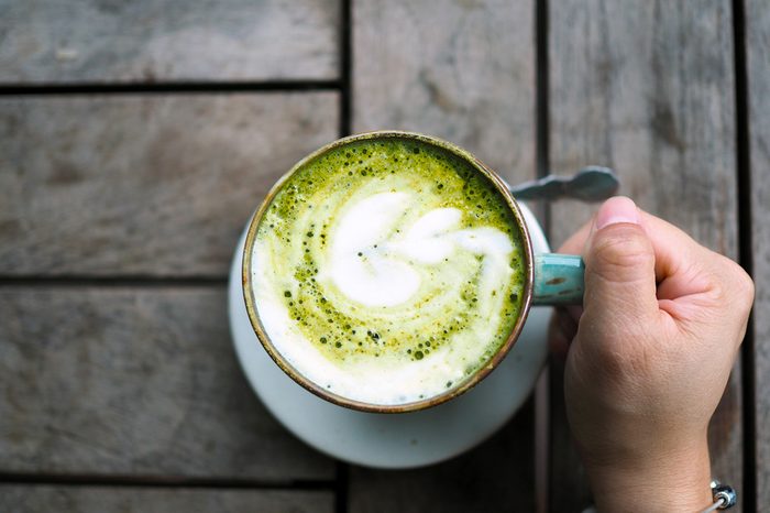 A ceramic cup of Japanese matcha latte with beautiful latte art on wooden table. Selective focus.