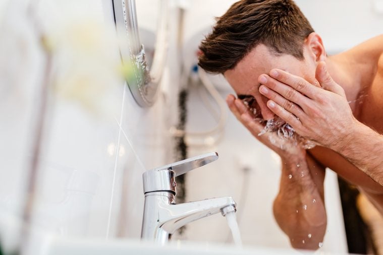 Man washing face in morning and practicing hygiene