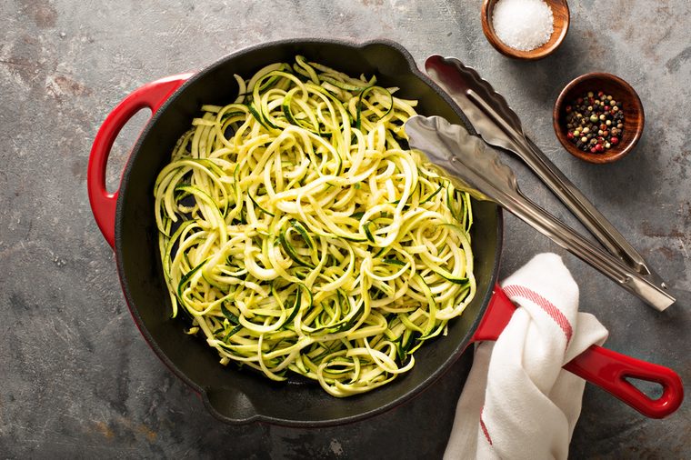 Cooked spiralized zucchini noodles in a cast iron pan overhead view, low carb dish