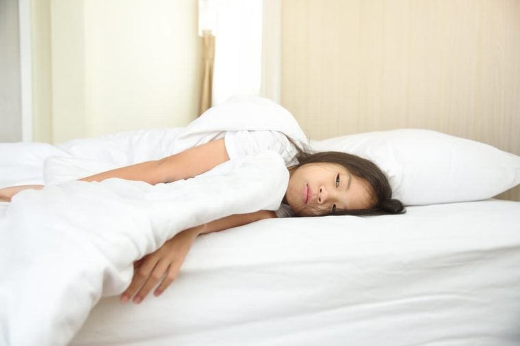 Do not want to wake up or illness concept. Portrait of lazy and touchy young Asian preteen age girl in bed waking up late. Unhappy sleepy kid get up late in the morning. 