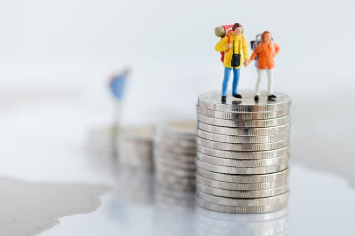 Miniature people: Two backpacker standing on rows of stack coins using as background Money, Financial, Business Growth and travel concept,