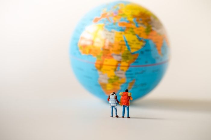 Miniature people: traveler mini figures with backpack standing looking at Global World map balloon. Success Business Due around the world and Traveling agency concepts