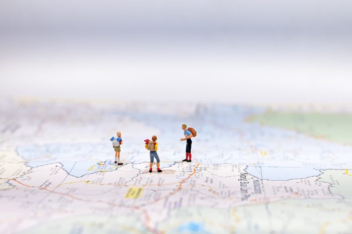 Miniature Group traveler with backpack standing on wold map for travel around the world. Travel Concept