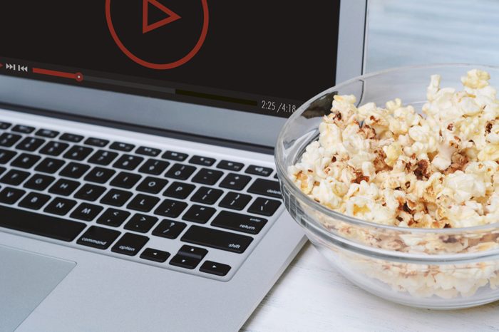 Popcorn in bowl and laptop playing movie. Entertainment concept
