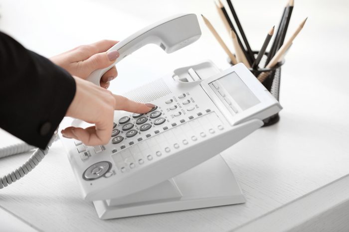 Woman using landline phone in office, closeup