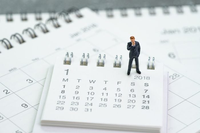 Miniature businessman thinking and standing on calendars using as business goals or future thinking.