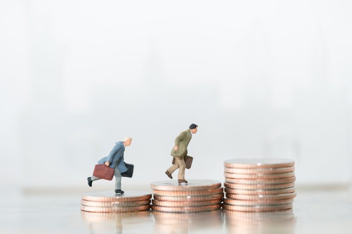 Miniature people: small figures businessmen walking and running on top of coins. Money, Financial, Business Growth concept.