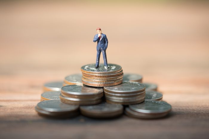 Miniature people, business man standing on stack of coins, financial, savings concept.