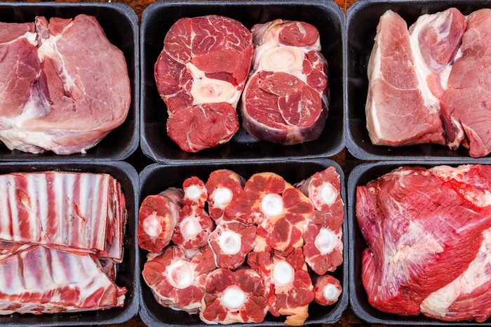 Different types of raw meat in plastic boxes, lamb shank on the bone, beef tail, beef neck, beef blade.