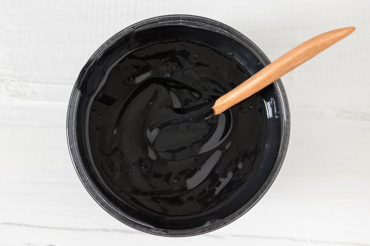 Homemade facial mask from activated charcoal powder and natural yogurt on white wooden background, skincare product