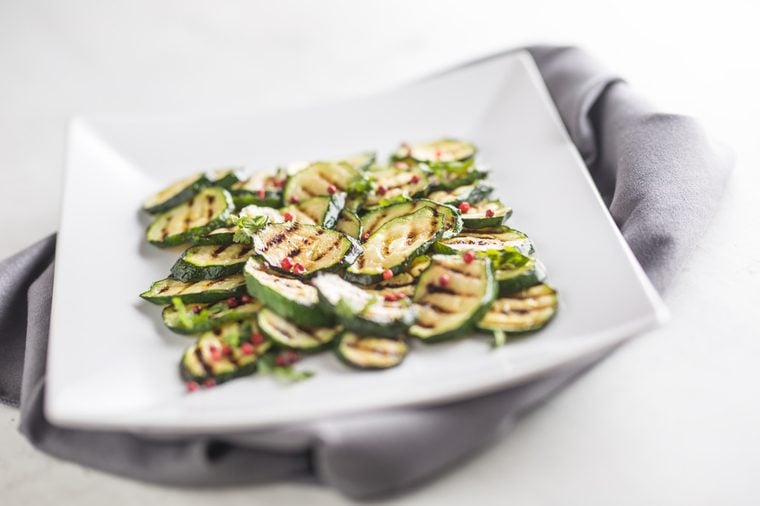 Grilled zucchini with red spice on white plate.
