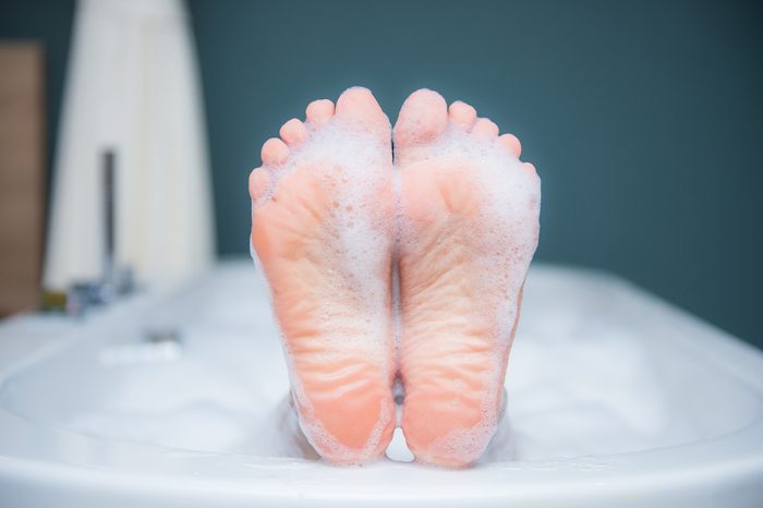 Closeup of woman's foot on the edge of a bath with foam, care