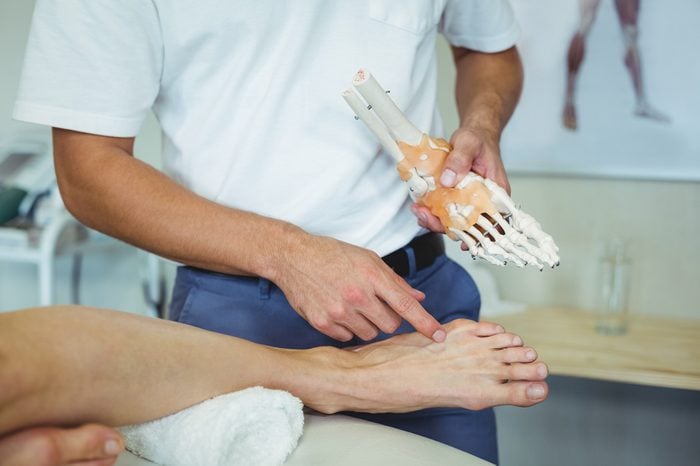 Physiotherapist explaining feet model to patient in clinic