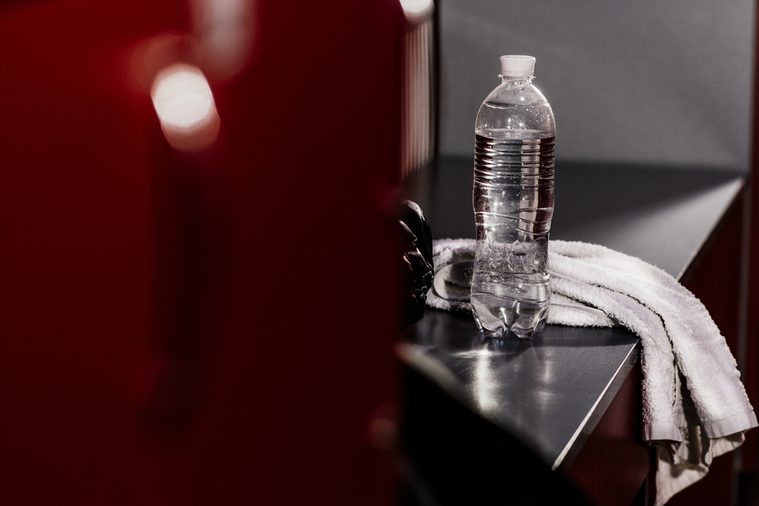 In the locker room of the gym. White towel boxing gloves, a bottle of water. advertising water. Accessories athlete. After a workout. Advertising Sports Club. Motivation to sport.