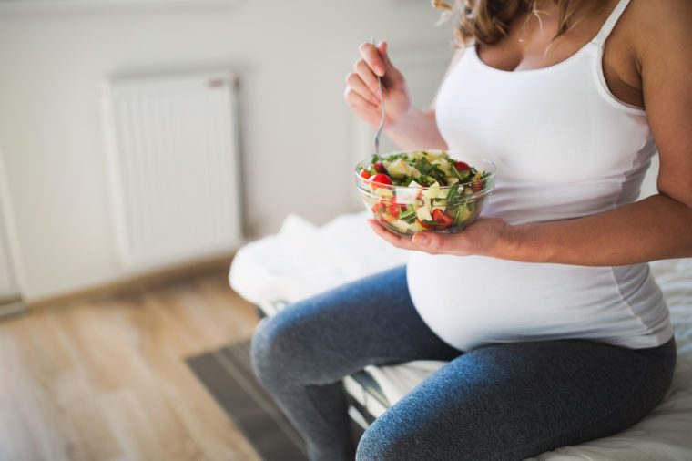 Pregnant beautiful woman eating healthy food and salads