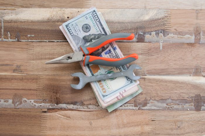 Money and worker concept. hundred dollar and tools on wooden table.