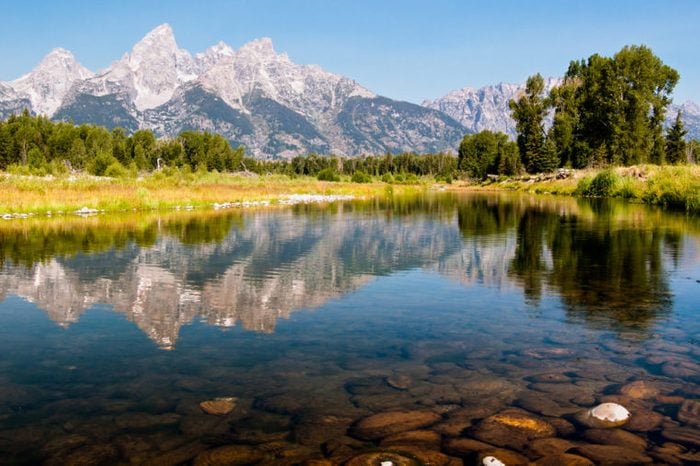 The Teton Mountain Range is reflected in the shallow and still waters of a braid of the Snake River in Grand Teton National park, Wyoming, USA