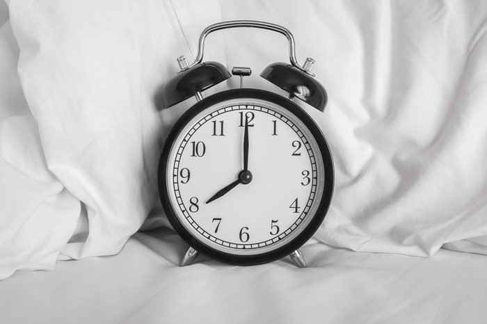 Still life with vintage alarm clock on bed ( alarm clock show 8 o`clock )