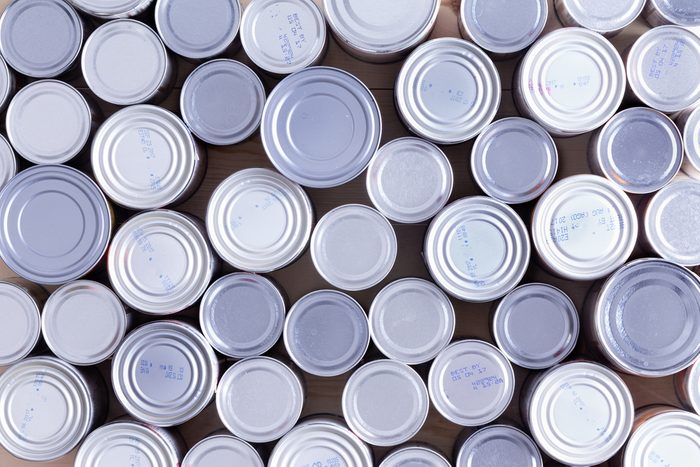Background of multiple sealed food cans or tins viewed from overhead in an assortment of sizes filling the frame in a food and nutrition concept