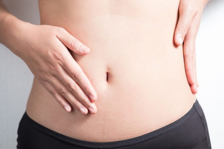 Pregnancy or diet concept, female hands protecting the stomach on white background.
