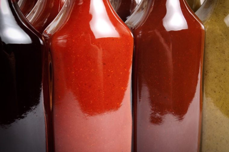 Closeup view of several glass bottles filled with various types of hot sauces.