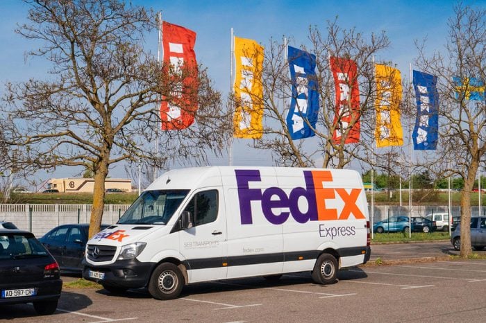 PARIS, FRANCE - APR 10, 2017: White FEDEX parcel delivery van parked in front of the IKEA furniture store with multicolor IKEA flags waving in the background