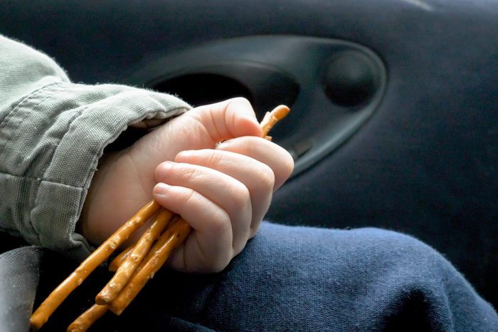 Closeup view child hand holding and eating biscuits while traveling in car