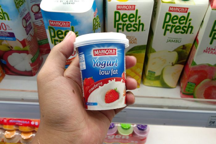 KLANG, MALAYSIA - MARCH 17, 2018 : Hand holding a cup of Marigold Low Fat Yogurt in hypermarket.