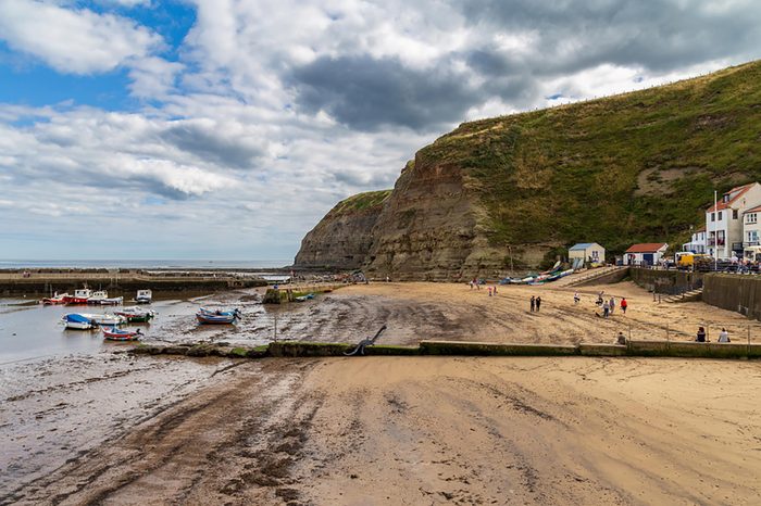 Staithes, North Yorkshire, England, UK - September 07, 2016: View across the beach with some boats and people