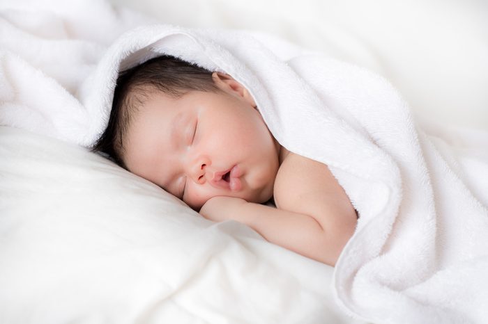A newly bathed newborn baby sleeps in a white towel