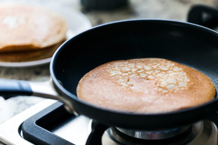 Making american pancakes on frying pan in kitchen interior, preparation breakfast food, nobody