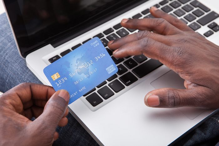 Close-up Of Hand Holding Credit Card And Shopping Online