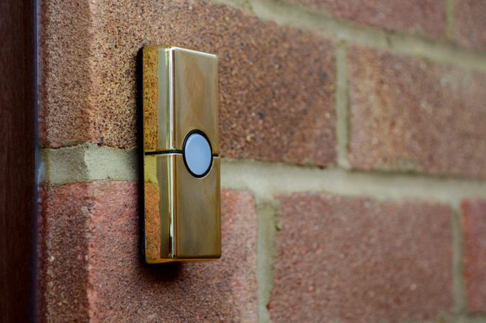 Gold or brass coloured doorbell on the brick wall of a house