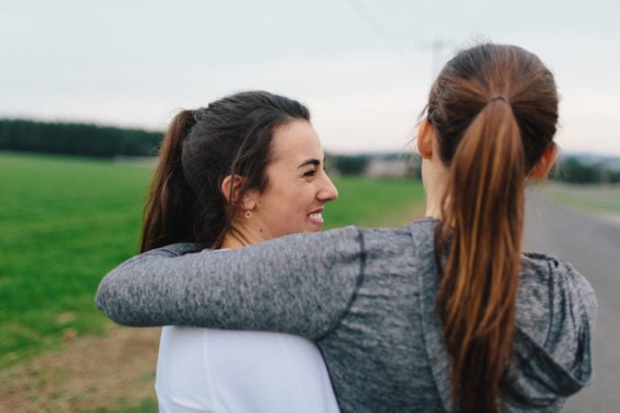 Two Beautiful Young Adult Women Arms around each other smiling