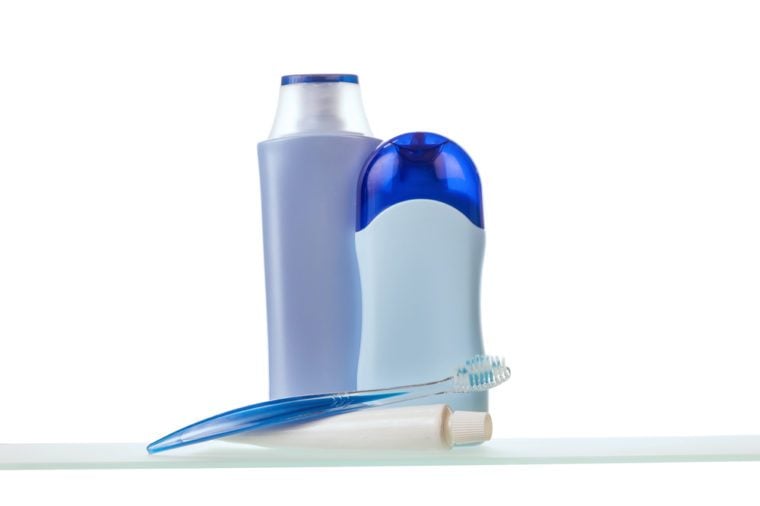Toothbrush, toothpaste and lotion with deodorant on glass shelf