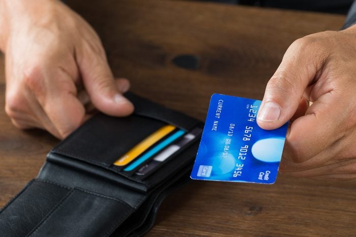 Cropped image of businessman giving credit card from wallet at desk