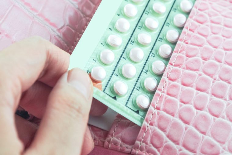 contraceptive pills in woman pink bag