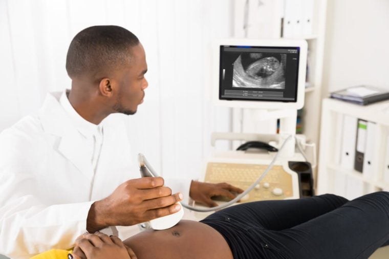 Gynecologist Checking Pregnant Woman's Belly With Ultrasound Transducer In Hospital