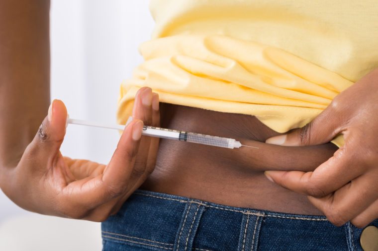 Close-up Of A Young Diabetic African Woman Injecting Stomach