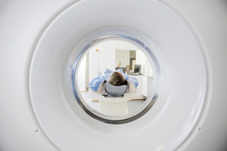 Woman Undergoing CT Scan While Doctor's Using Computers